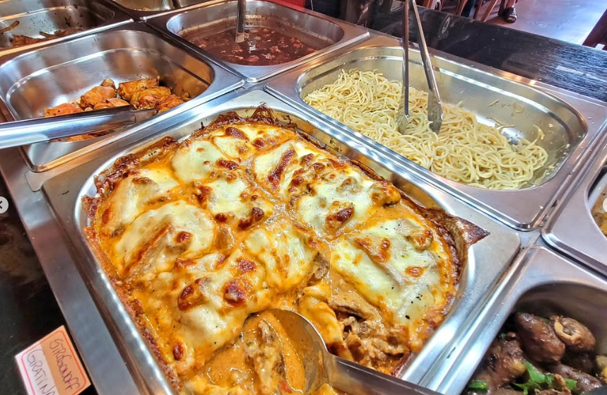 Lasanha gratinada servida no buffet com molho de queijo