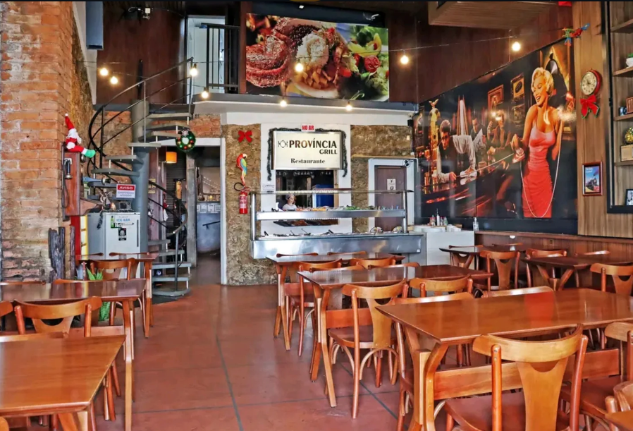 Salão principal do restaurante com mesas de madeira e parede de tijolos